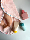 Baby lotion, bottle, and towel with a baby doll on a light gray background