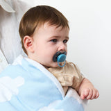 Baby with a pacifier wrapped in a blue blanket against a white background