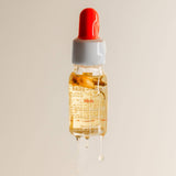 Bottle of skincare serum with a red cap and dropper on a beige background