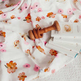 Wooden baby rattle on floral fabric with a book underneath