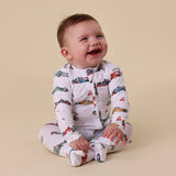Baby wearing a car-patterned onesie on a beige background