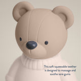 Teddy bear-shaped teether with text on a beige background