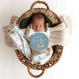 Newborn baby wrapped in a blanket with a 'Happy Easter' sign in a wicker basket.