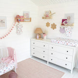 Children's bedroom with white dresser, crib, and decorative elements.
