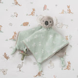 Gray koala plush toy with a mint green blanket on a patterned background