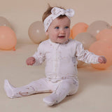 Baby sitting on a beige surface with balloons in the background