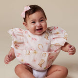 A smiling baby wearing a ruffled bib with a western boot and horseshoe print, sitting against a plain beige background.