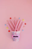 Floral-patterned cup with pink straws on a pink background