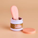 Jar of 'tiny tummies' ice cream with a pink spoon on a beige background