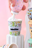 Colorful ice cream cups with cartoon designs on a pink background