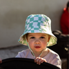 Child wearing a green and white checkered bucket hat outdoors.