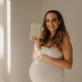 Pregnant woman holding a green box in a softly lit room