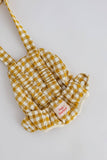 Yellow and white checkered apron with a pink label on a light gray background