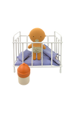 Toy baby in a crib with a bottle on a white background