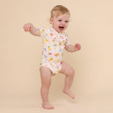 Baby in a colorful onesie standing on a beige background