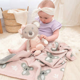 Baby playing with a plush toy on a pink blanket with koala designs.