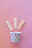 Ice cream cone with wafers and a cup on a pink background