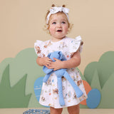 Child wearing a floral dress holding a blue teddy bear with a colorful background