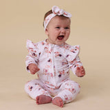 Baby wearing a floral onesie and headband on a beige background