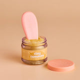 Jar of 'tiny tummies' banana custard with a pink spoon on a beige background