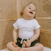 Child sitting on a toilet with a wicker wall background