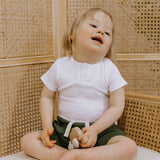 Child sitting on a toilet with a wicker wall background