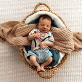 Baby sleeping in a woven basket with a blanket