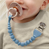 Baby wearing a blue teething ring with a pacifier attached