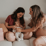Two women sitting on a couch with a baby