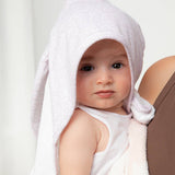 Baby wrapped in a towel with a hood, sitting on a white background
