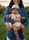 Woman holding a baby outdoors with a toy, smiling
