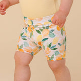 Child wearing shorts with a lemon pattern on a beige background