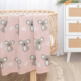 Pink blanket with koala pattern draped over a crib in a nursery setting.