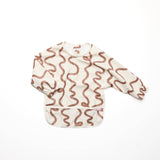 Baby bib with brown wavy pattern on a white background