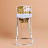 White high chair with a green and yellow checkered cushion on a beige background