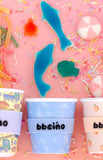 Colorful ice cream cups with 'bbeeino' branding on a pink background with candy and sprinkles.