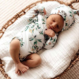Newborn baby sleeping in a wicker basket with floral outfit and hat.