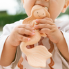 Child holding a wooden angel toy outdoors