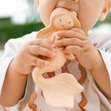 Child holding a wooden angel toy outdoors