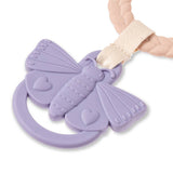 Purple butterfly-shaped teething toy with a heart design, held by a hand against a white background.