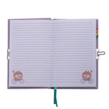 An open lined notebook with a lavender cover, featuring two small illustrated carriage motifs near the bottom corners of each page and a teal ribbon bookmark hanging from the center.