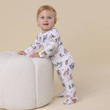 Baby in a floral outfit standing on a beige background