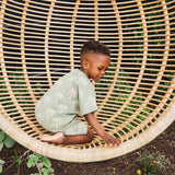 Child sitting on a large wicker chair outdoors