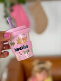 Pink cup with cartoon designs and 'bbqino' text held by a hand.