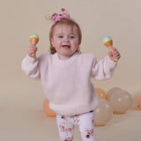 Child holding colorful maracas with balloons in the background
