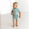 Child wearing a light blue outfit standing on a white background