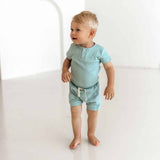 Child wearing a light blue outfit standing on a white background