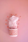 Pink cotton candy in a cup on a pink background with decorative flowers.