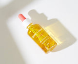 Bottle of Bare Nud oil with a white pump on a light background