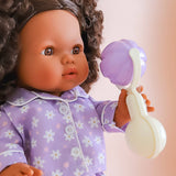 Doll in a purple outfit holding a toy with a soft focus background